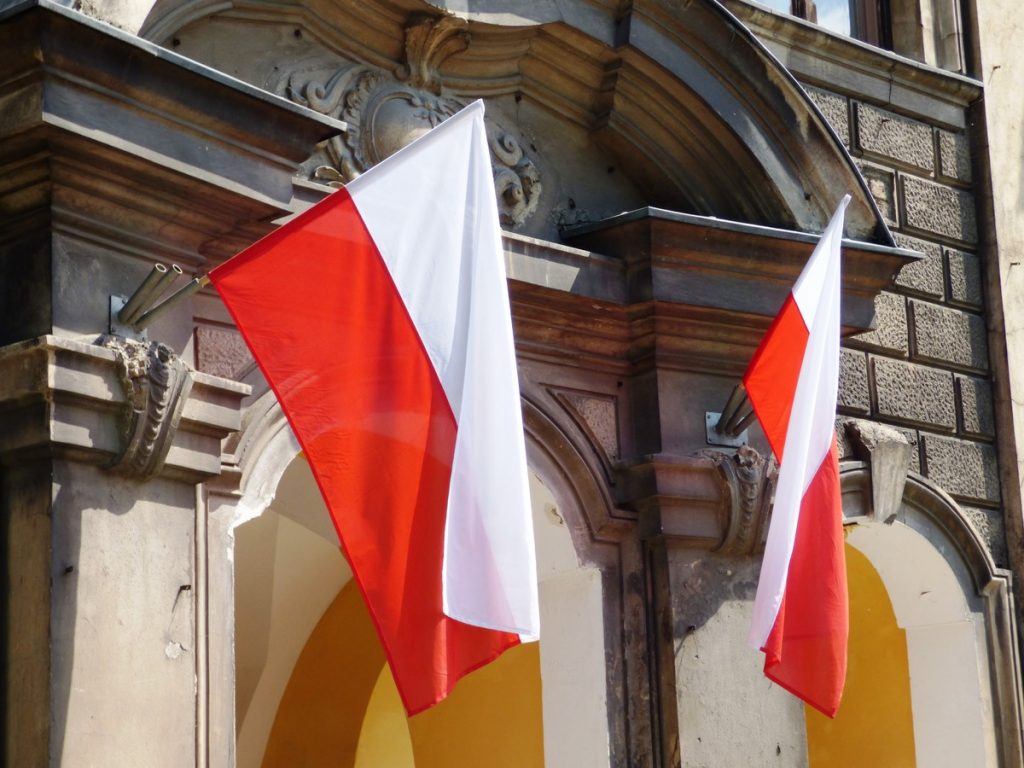 Dwie flagi biało-czerwone powieszone przy wejściu do budynku