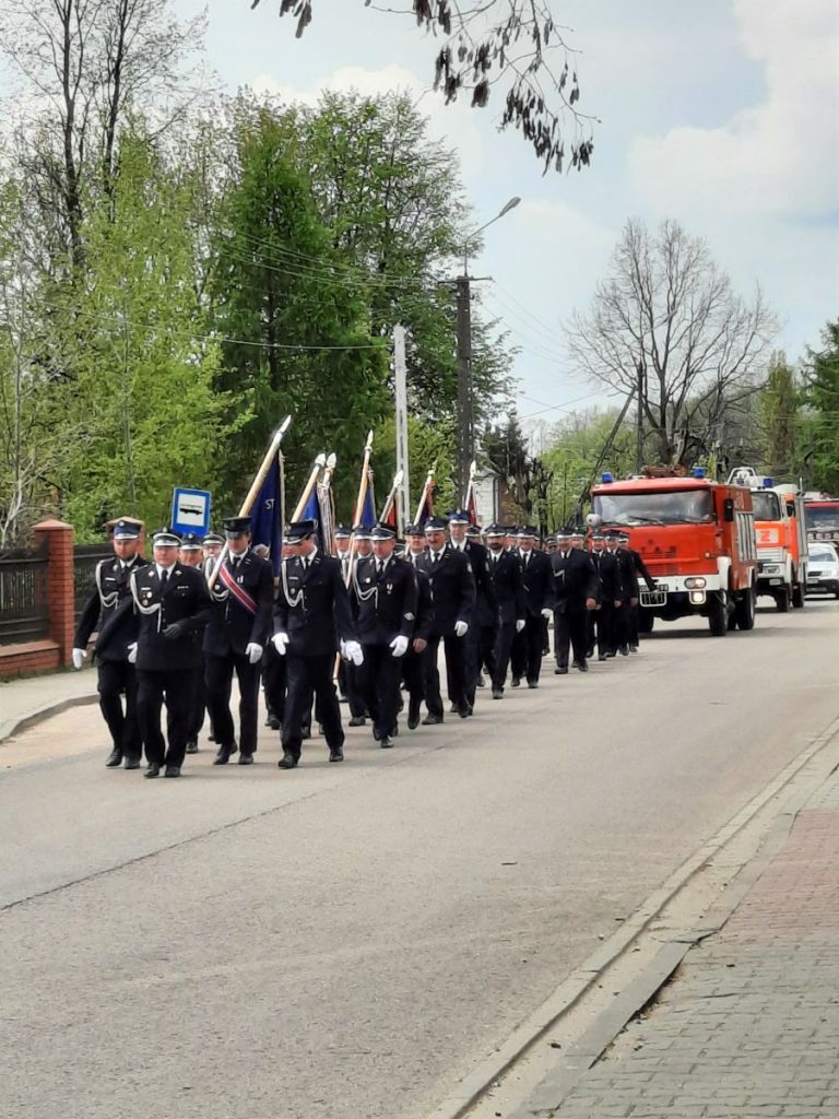 Zdjęcie przedstawia strażaków w mundurach wraz z pocztami sztandarowymi.