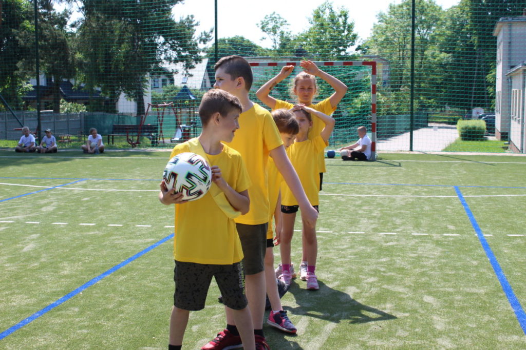 dzieci uczestniczą w zawodach sportowych, biegają, rzucają piłką.