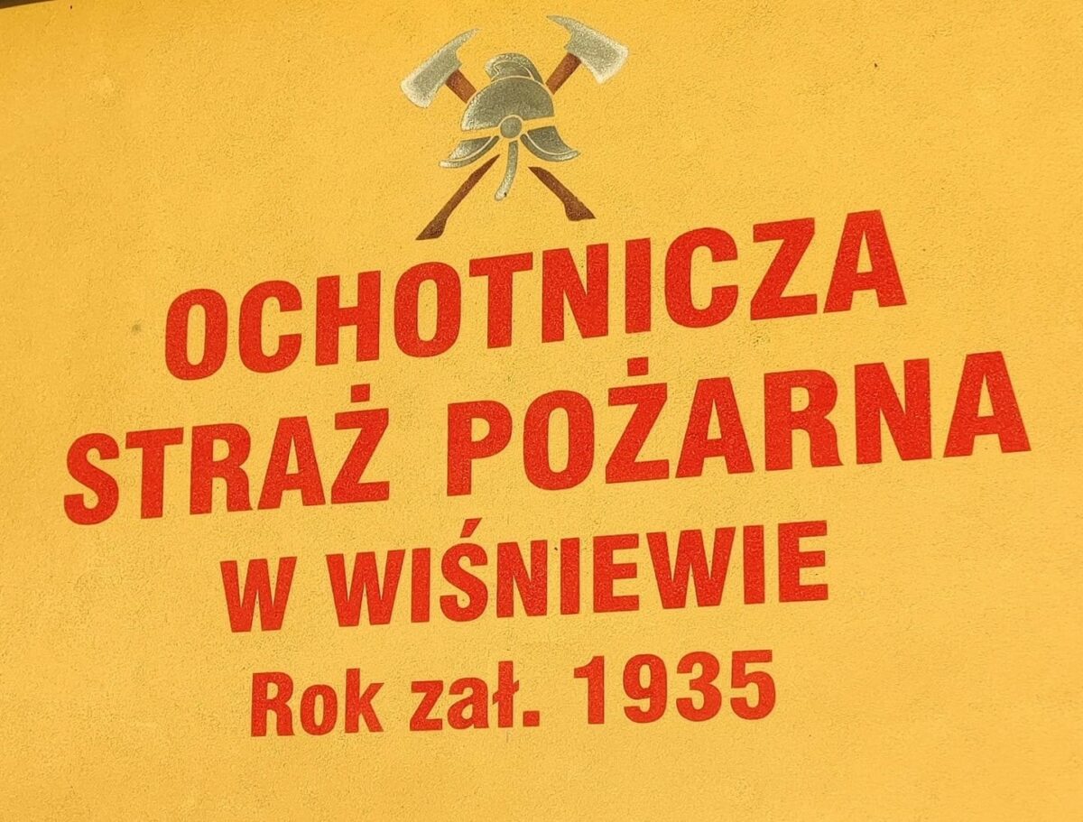 Napis na żółtym tle OCHOTNICZA STRAŻ POŻARNA W WIŚNIEWIE Rok zał. 1935