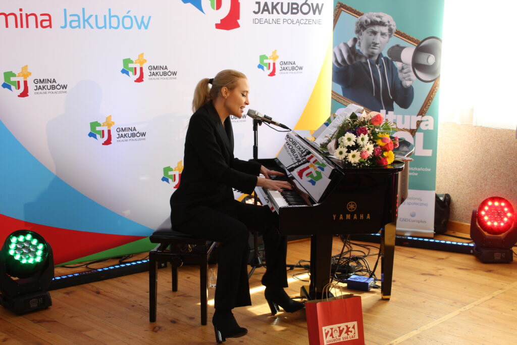 Zdjęcia przedstawiają relację z koncertu w sali OSP Jakubów. Występujący i goście na krzesłach.