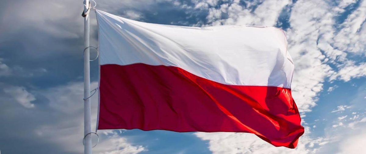 biało-czerwona flaga na maszcie w tle niebo z chmurami