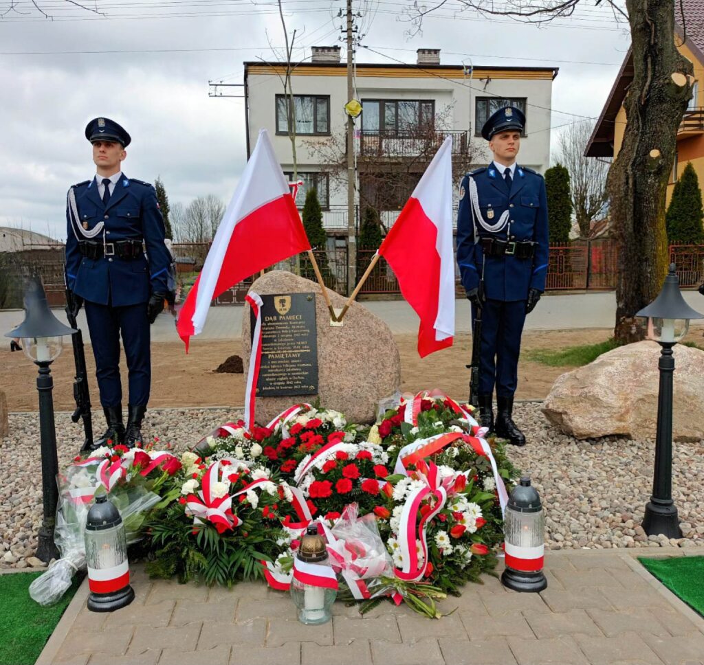 Na zdjęciach widać dwóch policjantów oraz dwóch uczniów szkoły policyjnej pełniących wartę honorową, obok kamienia upamiętniającego, zamordowanych w Katyniu. Na kamieniu powiewają 2 flagi biało czerwone oraz pod kamieniem złożone są biało czerwone wieńce i kwiaty.