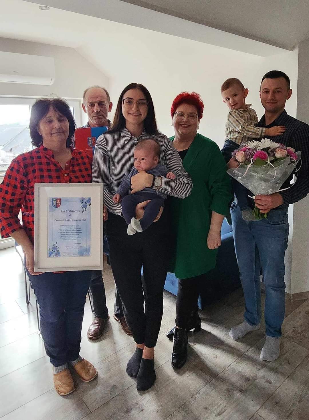 Na obrazku rodziny: matkę, ojca i małe dziecko. trzymają się oni w ramionach oprawionych certyfikatów, który zostaje uderzony ich ciężarem i radością.