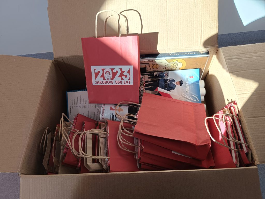 Na obrazku pudło wypełnione czerwonymi papierowymi torebkami oraz książkami. Torebki i książki są stosowane w przypadku stosowania, co do przygotowania niektórych wydarzeń lub dystrybucji.