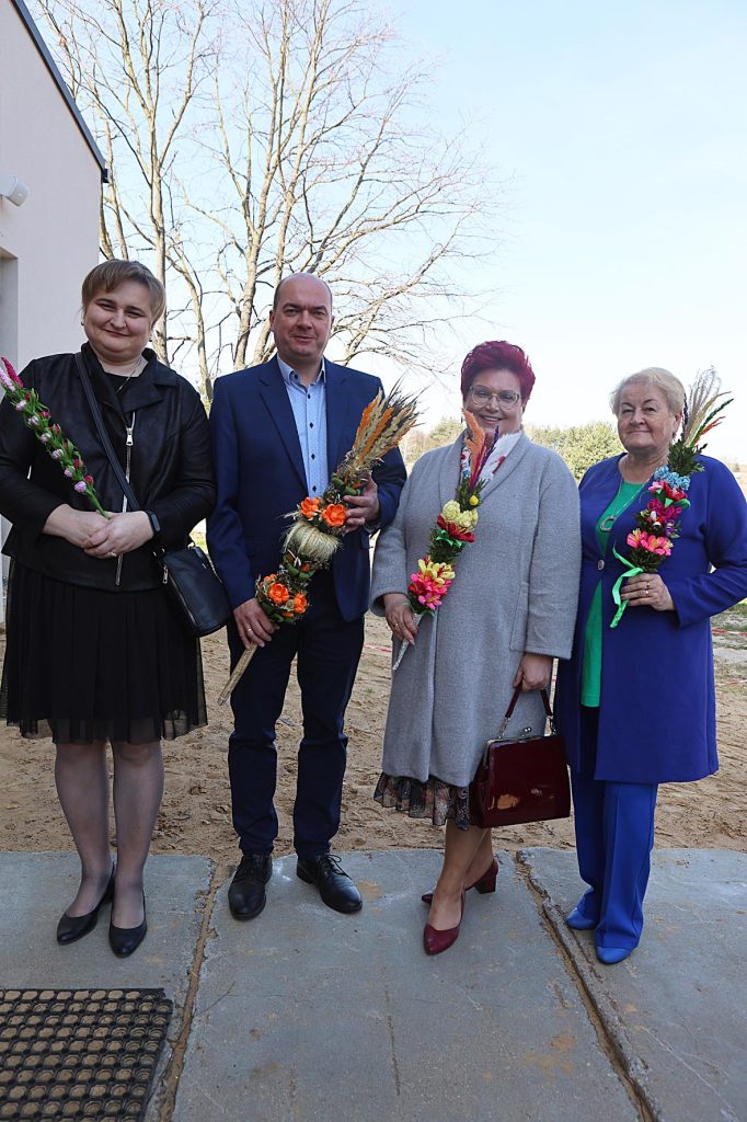 Na zestaw składają się cztery osoby, które są stosowane na zewnątrz, ubranie w, ale swobodne stroje. trzymać osobę trzymaną w rękach kompozycję kwiatową i czuć się do aparatu.
